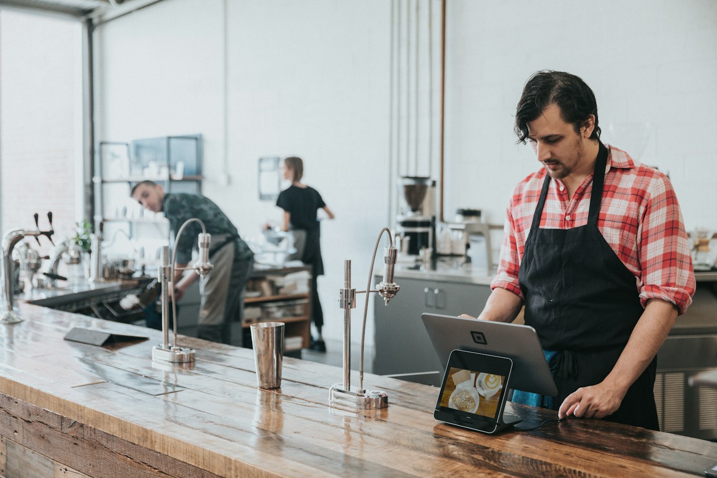 A café owner checking enquiries on a tablet at the counter