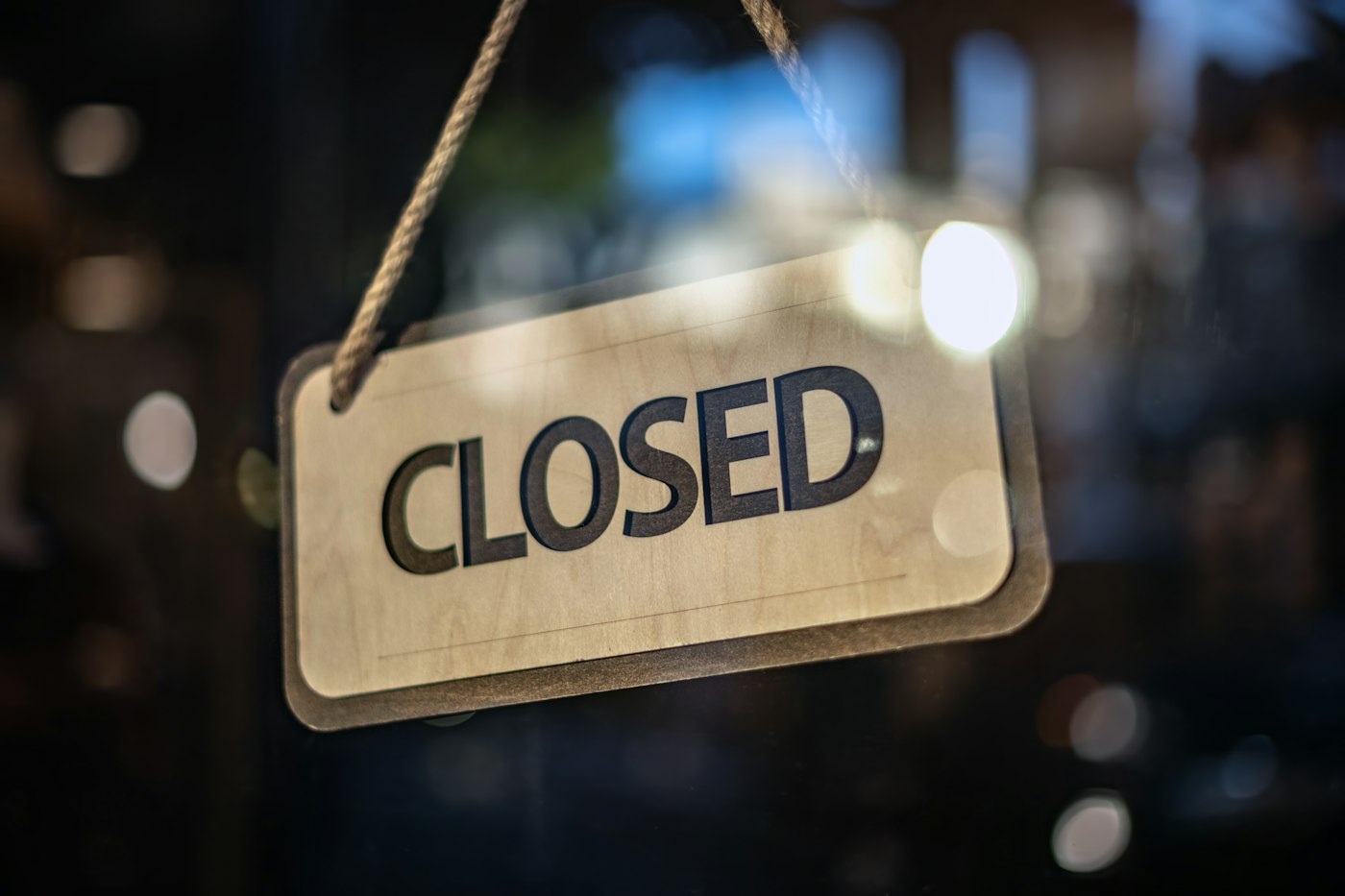 A closed sign hanging in a shop door at night