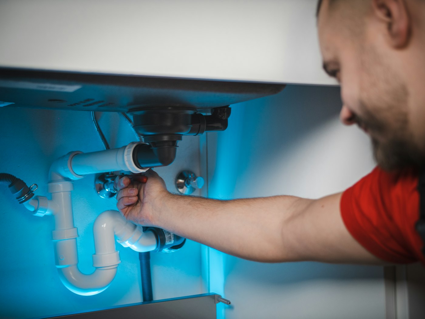 A plumber fixing the pipes under a sink