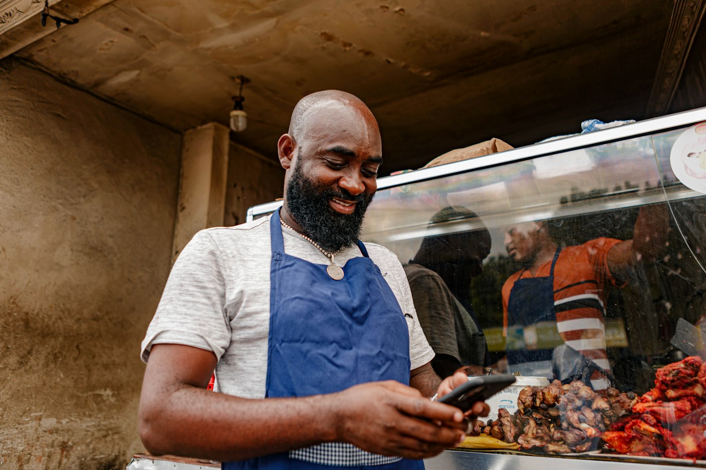 A stallholder smiling as he reads a text message
